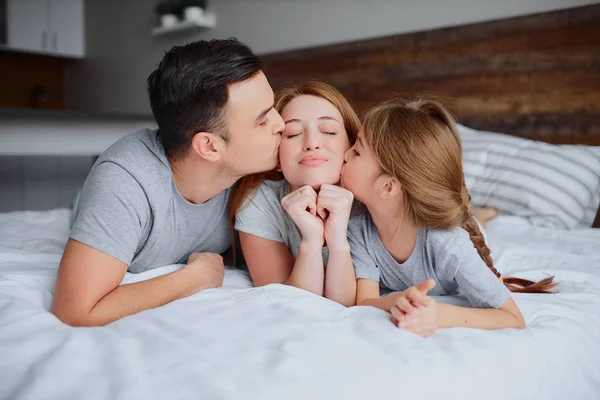 Jeune famille avec enfant embrassant sur le lit — Photo