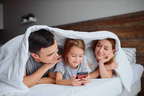 Portret van gelukkig gezin liggend op bed samen — Stockfoto