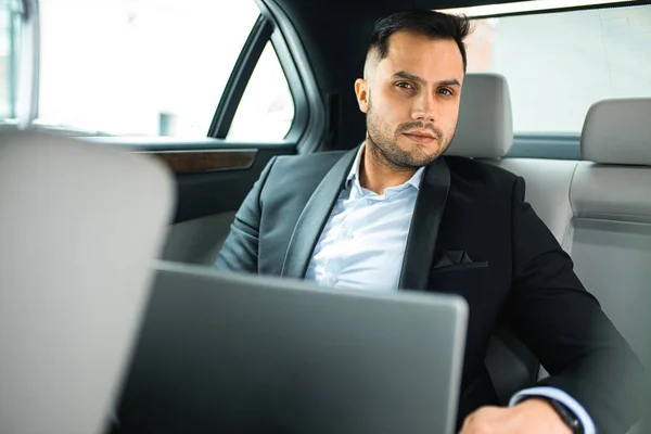 Mann in offizieller Kleidung mit Laptop im Luxusauto — Stockfoto