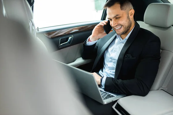 Jungunternehmer im eleganten Anzug auf dem Rücksitz eines Luxusautos — Stockfoto