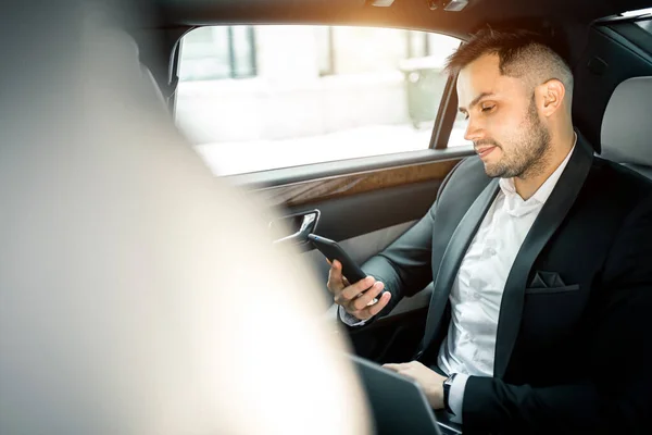 Junger Kaukasier schaut auf Bildschirm des Smartphones im Auto — Stockfoto