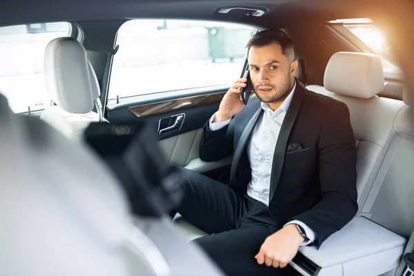 Eleganter Mann sitzt in luxuriösem Auto und telefoniert — Stockfoto