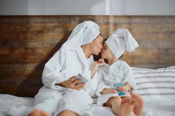 Hermosa madre e hija usando teléfono inteligente en la cama en casa — Foto de Stock