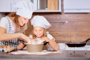 Güzel anne, kızıyla mutfakta para kazanıyor.