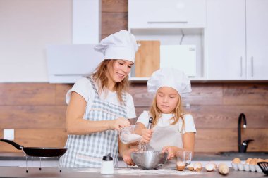 Genç anne ve çocuk birlikte yemek pişiriyorlar.
