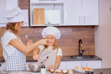 Mutfakta yemek pişirirken eğlenen anne ve kızın portresi