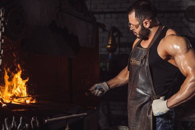 Atölyede metali ısıtan sakallı adamın yan görüntüsü