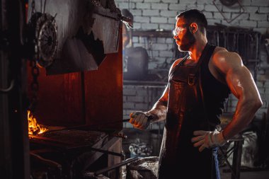 Atölyede metali ısıtan sakallı adamın yan görüntüsü