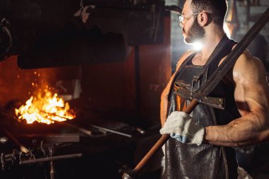 Kaslı kalpazan erkek demircilik yapıyor.