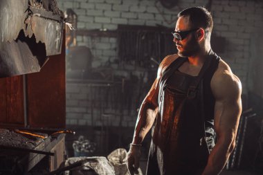 Kalorifer ocağına bakan demircinin yan görüntüsü
