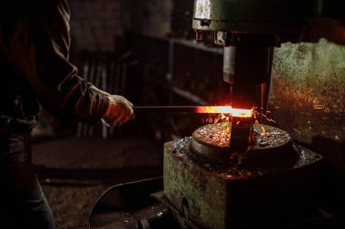 Kafkasyalı genç metal işçisi atölyede ısıtılmış metalle çalışıyor.