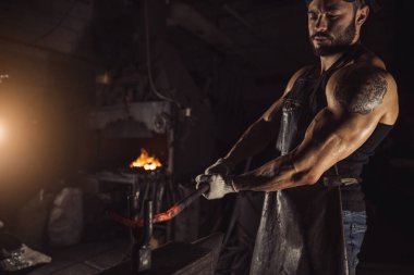 Yandan bakıldığında sıcak metali örste ısıtan adam görülüyor