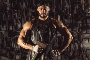 Siyah önlüklü kendinden emin genç metal işçisinin portresi.
