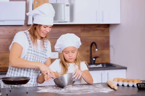 Caucasian child mixing flour in bowl with mother in kitchen — Stock Photo, Image
