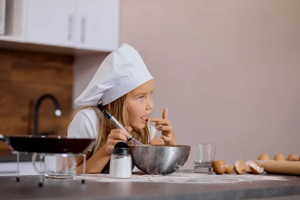Piccola ragazza caucasica cercando pasta durante la cottura — Foto Stock