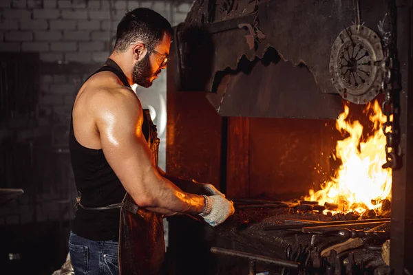 Ferreiro muscular forte prepara ferro no fogo — Fotografia de Stock