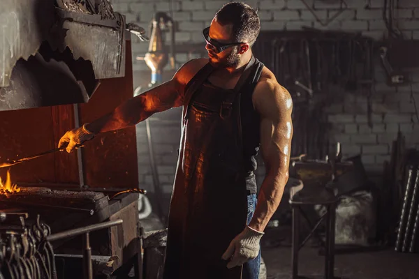 Herrero caucásico hace productos de hierro para la fabricación de chimeneas, estufas — Foto de Stock