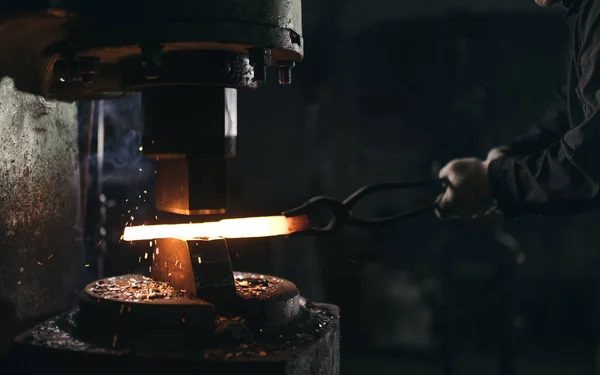 Herrero utilizando prensa hidráulica para la fabricación de armas de acero en taller de herrería — Foto de Stock