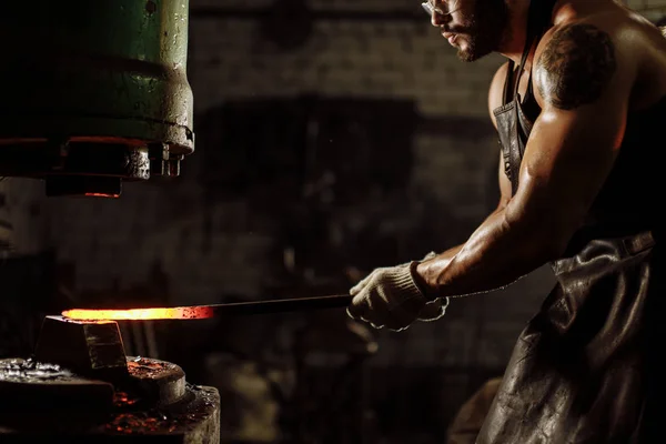 Herrero utilizando prensa hidráulica para la fabricación de armas de acero en taller de herrería — Foto de Stock