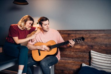 İki pozitif genç arkadaş oturup gitar çalar ve dinlerler.