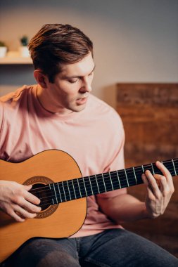 Genç adam gitar çalıyor ve şarkı söylüyor.
