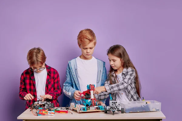 Edukacja, nauka, koncepcja technologii. kaukaskie dzieci z elektrycznymi zabawkami i robotami budowlanymi — Zdjęcie stockowe