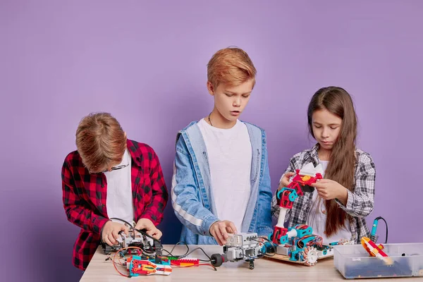 Образование, наука, технологическая концепция. Кавказские дети с электрическими игрушками и роботами-строителями — стоковое фото