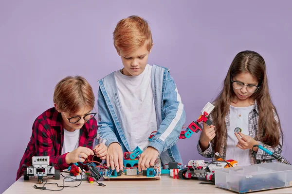 Retrato de três crianças caucasianas interessadas em brinquedos futurísticos — Fotografia de Stock