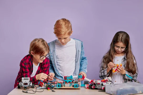 Smarta kaukasiska pojkar och flicka intresserad av futurustiska leksaker — Stockfoto
