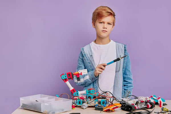 Kind montiert Roboter auf Tisch isoliert — Stockfoto