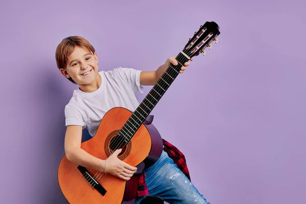 Junge spielt Gitarre isoliert vor lila Hintergrund — Stockfoto