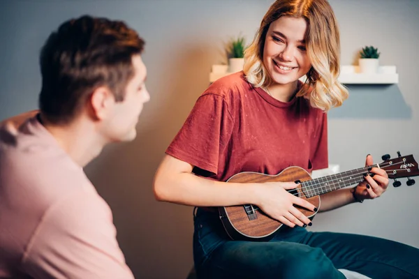 Ładna kobieta pokaż gra w ukulele dla młody facet — Zdjęcie stockowe