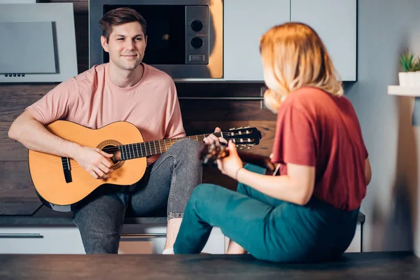 Dos jóvenes amigos positivos se sientan tocando la guitarra y escuchan — Foto de Stock