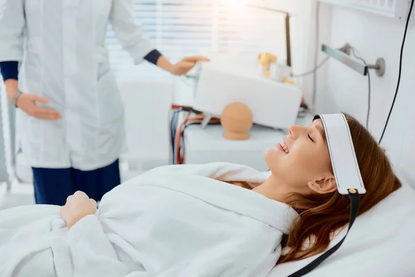 Atractiva hembra acostada en la cama en el hospital y sonrisa —  Fotos de Stock