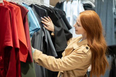 Alışveriş merkezinden kıyafet seçen hoş beyaz bir kadın.