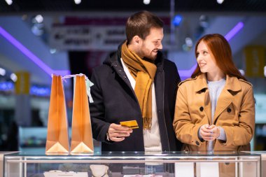 Mutlu, genç, romantik çift mücevher dükkanından altın yüzük alıyor.