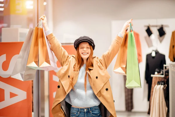 Vrolijke vrouw het verhogen van de handen met papieren tassen na het winkelen — Stockfoto