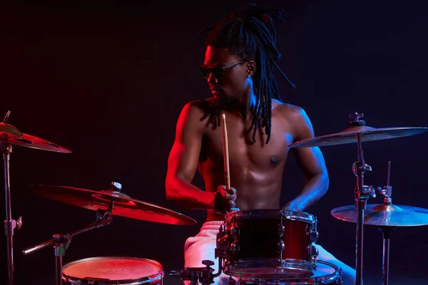 Uomo africano attivo che suona alla batteria impostato in luci al neon — Foto Stock