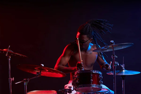 Expressivo homem negro articulado tocando bateria isolada sobre fundo de néon — Fotografia de Stock