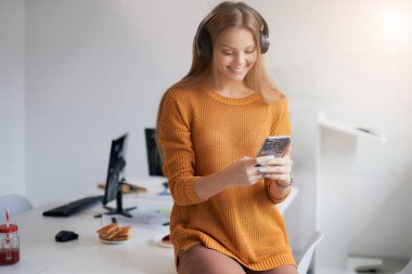 Genç iş kadını ofiste boş zamanlarında müzik dinler.