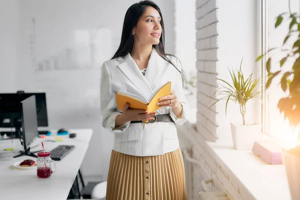 Mujer de negocios reflexiva sosteniendo el libro en la oficina — Foto de Stock
