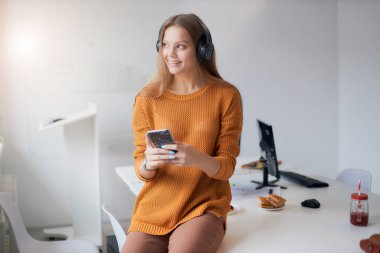 Gülümseyen iş kadını iş yerinde dinleniyor.