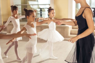 Genç beyaz kadın genç kızlara klasik bale yapmayı öğretiyor.