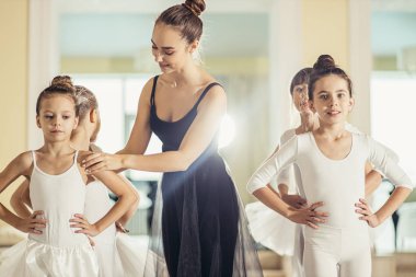 Genç beyaz kadın genç kızlara klasik bale yapmayı öğretiyor.