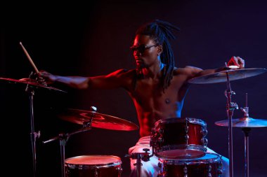Neon ışıklarda bateri çalan aktif bir Afrikalı.