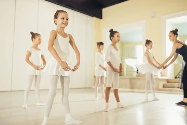 Attractive slim ballerina in black tutu skirt show right poses in ballet to kids — Stock Photo, Image