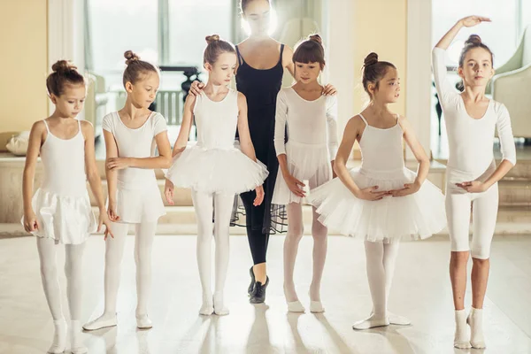 Young woman ballet teacher and kids stand on tiptoes in studio — Stock Photo, Image