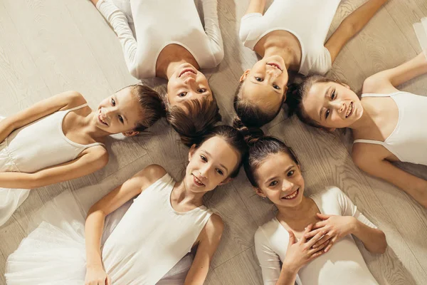 Милые маленькие девочки-балерины лежат на полу в кругу — стоковое фото