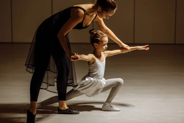 beautiful woman ballerina teaching little girl to dance classic ballet