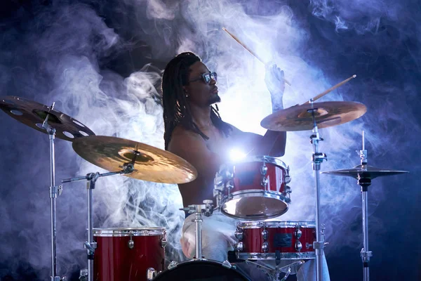Silueta del batería hombre sentarse golpeando los tambores aislados sobre el humo —  Fotos de Stock